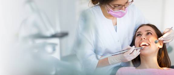 Eine Zahnärztin behandelt eine lächelnde Patientin im Behandlungsstuhl